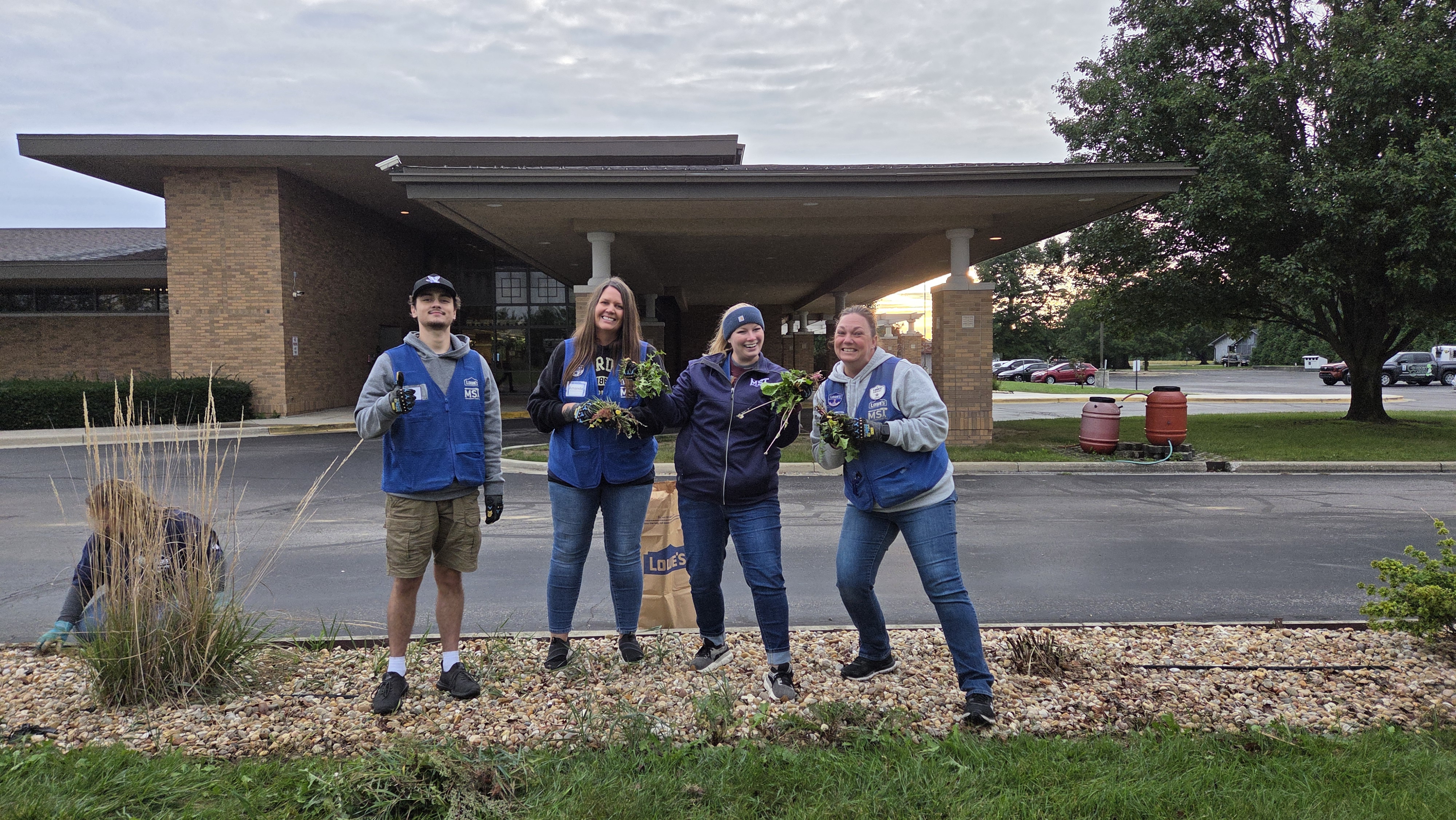 Volunteers smiling for a picture while weeding