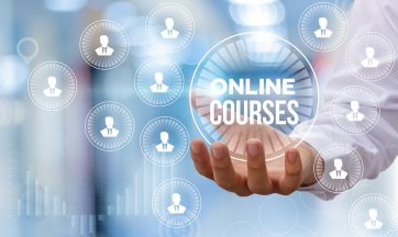 Photo of a hand holding the text Online Courses. There are various icons floating around it