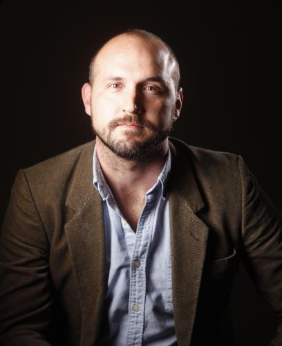 Portrait Photograph of Ben Montgomery. Black background with a white male looking towards the camera